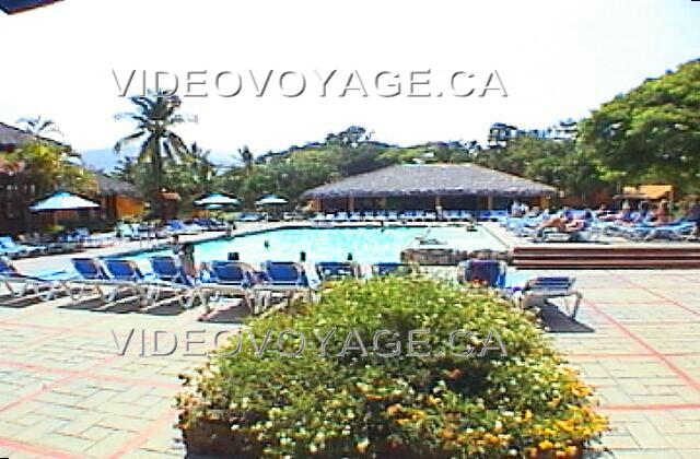 Republique Dominicaine Puerto Plata Holiday Village Golden Beach A droite de la piscine la terrasse est surélevé et beaucoup de chaises longues y sont disposées. Les chaises sont recouvertes de tissus. Peu de parasols sont disponibles.