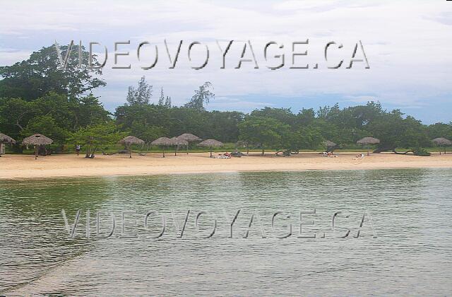 Cuba Guardalavaca Playa Pesquero Des parasols et quelques chaises longues entre les arbres sur la plage.