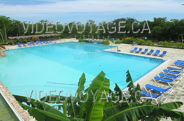 Cuba Guardalavaca Memories Holguin Beach Resort A un niveau inférieur, une plus grande piscine.  Quelques chaises longues et des palapas.