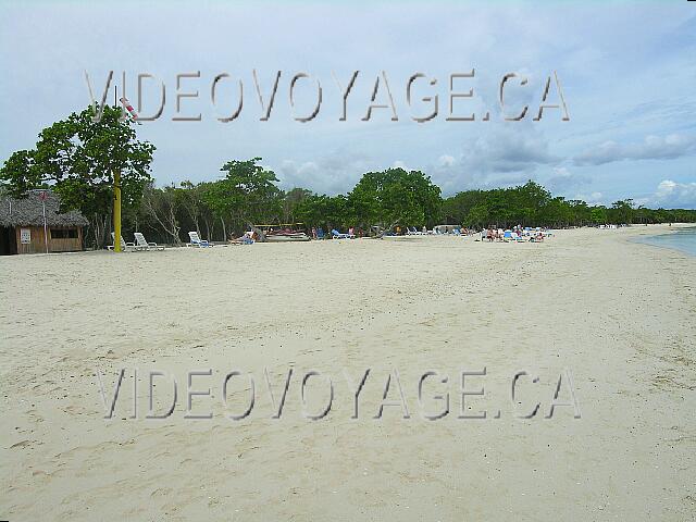 Cuba Guardalavaca Memories Holguin Beach Resort Tumbonas, pero no hay sombrillas. Clientes habritent bajo los árboles en la playa. No hay palmeras en la playa.