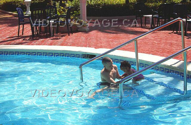 Republique Dominicaine Punta Cana Vista Sol Punta Cana Un padre está ayudando a los niños a entrar en la piscina. Las rampas están disponibles para ayudar a las personas con ciertas discapacidades.