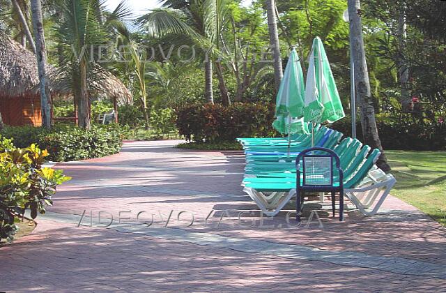 Republique Dominicaine Punta Cana Grand Palladium Punta Cana Res Des chaises longues en tissus et des parasols en tissus sont disponible autour de la piscine. La végétation étant abondante, seulement certains endroits avec des chaises sont ensoleillé pendant une longue durée.