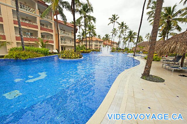 République Dominicaine Punta Cana Majestic Elegance Una piscina larga, una terraza en un lado con varias sillas y palapas.