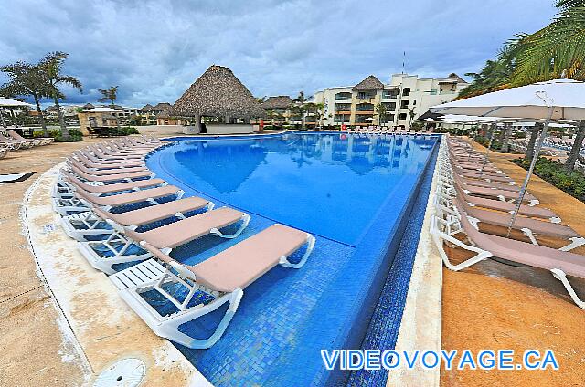 République Dominicaine Punta Cana Hard Rock Punta Cana La piscine Central, avec plusieurs chaises longues dans la piscine, plusieurs chaises longues sur la terrasse et quelques parasol.  Le bar sur la terrasse.