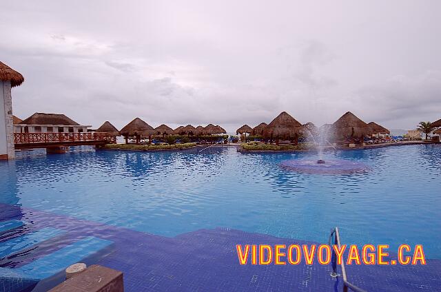 Mexique Puerto Morelos Sapphire Riviera Cancun Une fontaine au centre de la piscine.  De l'autre coté de la piscine, de nombreux palapas.