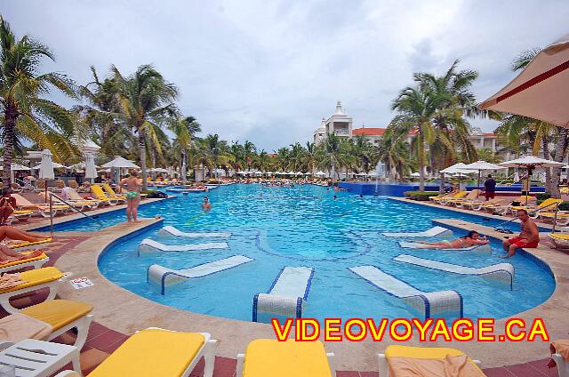 Mexique Playa Del Carmen Palace Riviera Maya Une piscine longue, avec de nombreuses chaises longues avec coussin et de nombreux parasols.