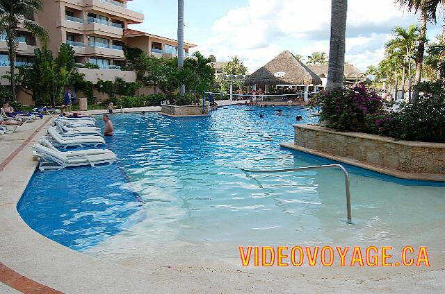 Mexique Puerto Aventuras Dreams Puerto Aventura El descenso a la piscina con una rampa en el centro. A la izquierda, varias sillas en la piscina. Al final de la tarde, el sol se oculta por el edificio.